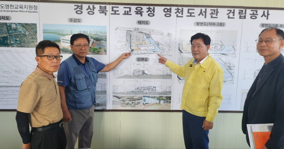 윤승오 도의원이 도서관 조감도를 보면 현장소장과 건물 입구, 경계 지점 등에 대해 대화하고 있다.